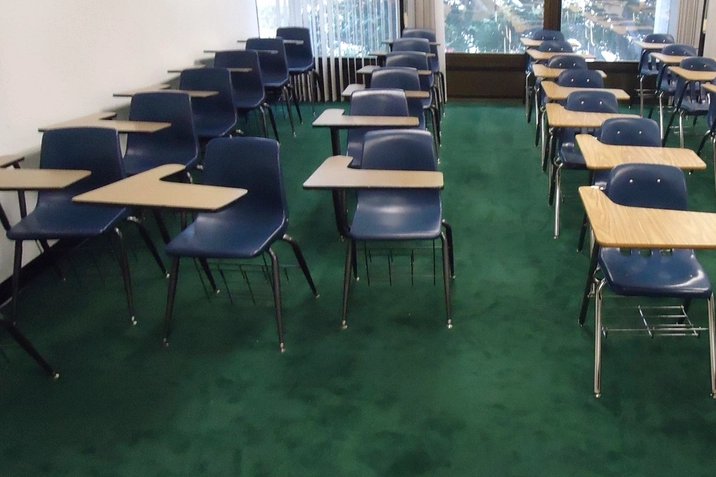 Empty classroom desks facing a chalkboard