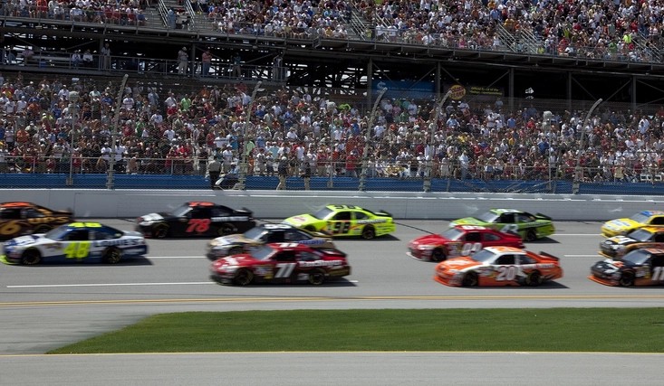 Stock cars racing side by side on an oval