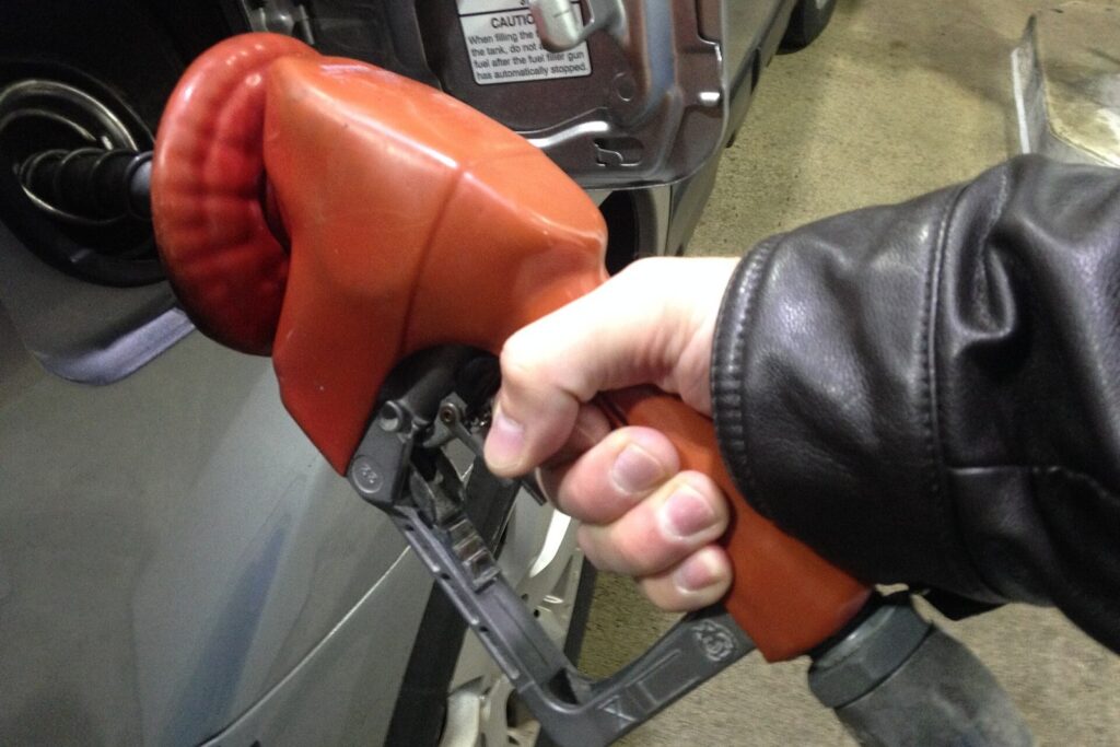 Hand pumping gas into a car at a fuel pump